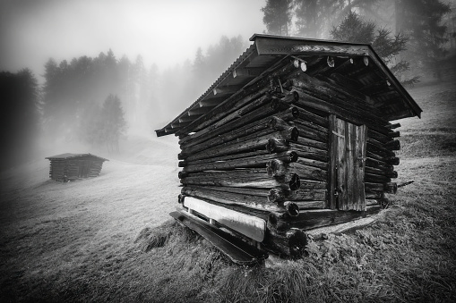 Mountain wooden hayloft in the Stubai Alps with fog in the background