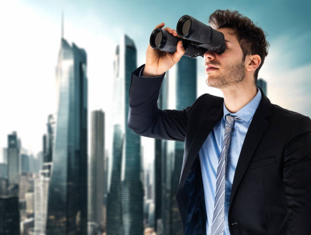istock Giant businessman looking through binoculars in a metropolis 1992940212