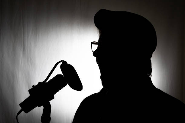istock Voiceover artist silhouette in studio with microphone and hat 1992951784
