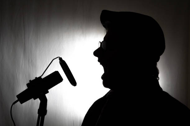 istock Voiceover artist silhouette in studio with microphone and hat 1992951787