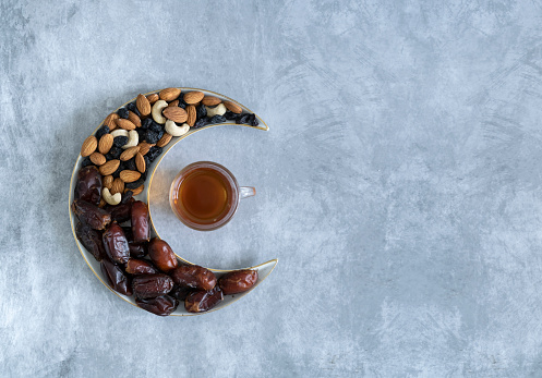 Dry fruits and nuts on a crescent moon shape plate with Black tea, Iftar background, Ramadan concept image with copy space