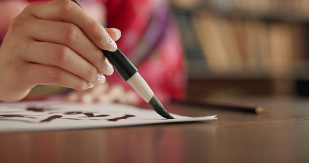 istock Ink, Japanese writing and person in traditional home for script, documents and paper on desk. Creative, Asian culture and hands with vintage paintbrush tools for calligraphy, font and text in house 1993022788