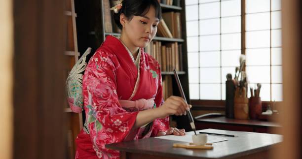 istock Ink, writing and traditional Japanese woman in home for script on paper, documents and page. Creative, Asian culture and person with vintage paintbrush tools for calligraphy, font and text in house 1993022791