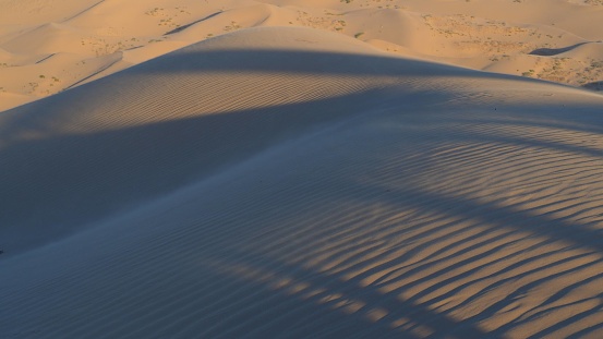 Embark on a visual odyssey into the heart of the enchanting Glamis Sand Dunes and its breathtaking surroundings. In this mesmerizing snapshot, the desert landscape unfolds in a symphony of golden hues, where each ripple of sand whispers tales of timeless allure. Towering dunes stand as majestic sentinels, their curves and crests casting intricate shadows beneath the radiant sun. As far as the eye can see, the desert vista stretches, a canvas of serenity punctuated by the occasional silhouette of hardy flora. Against the backdrop of an endless azure sky, the dunes beckon adventurers to explore their mysterious depths, promising a journey filled with wonder and awe. From the windswept dunes to the distant horizons, this photograph captures the essence of untamed beauty and invites all to lose themselves in the spellbinding allure of nature's grandeur.\