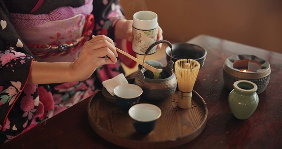Traditional, matcha and Japanese woman with tea in home with herbs, powder and flavor in teapot. Ritual, indigenous culture and hand of person with herbal beverage for drinking, ceremony and wellness