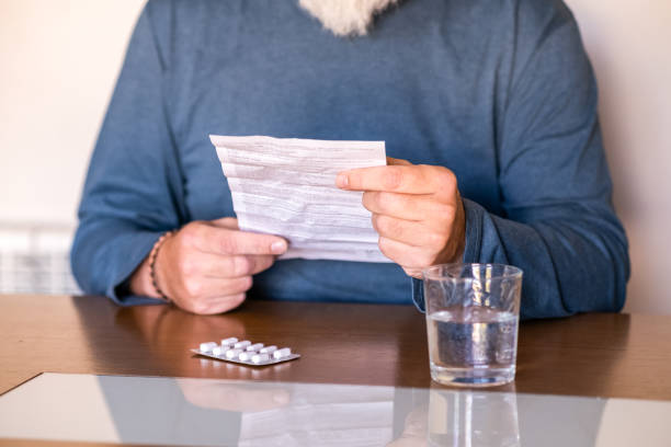 An adult male reads the leaflet of a drug before taking it. stock photo