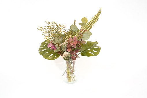 Wilted Gerbera flower in brown vase on wooden table over white background.