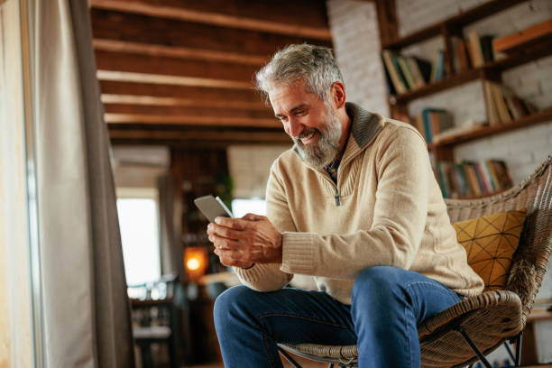 istock Cheerful mature man using cellphone at home. 1993091046