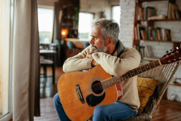 istock Pensive man with acoustic guitar at home. 1993092081