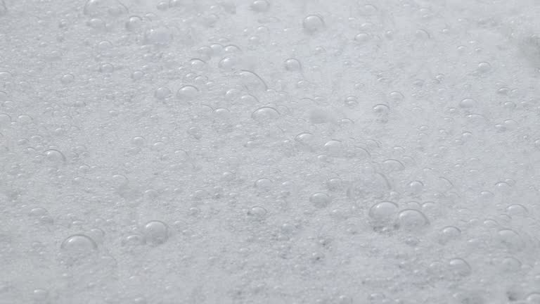 In this serene slow-motion video, a close-up captures many bubbles and white foam gently cascading.