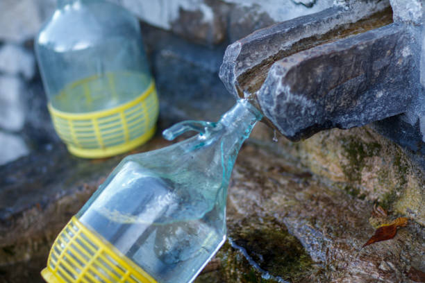 a glass re usable 5 liter bottle collecting spring untreated river mineral water from source in the mountain for human consumption