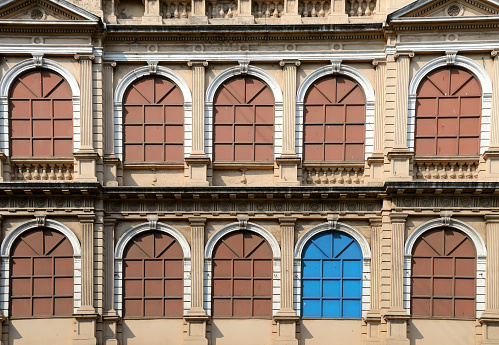 Odd man out. Architectural details showing one metal window of a different color out of rows of other similar windows.