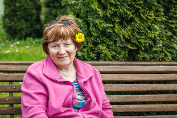 행복 한 미소 노인 여성의 초상화는 봄에 정원의 벤치에서 휴식을 취하고 있습니다. - senior women senior adult bench flower 뉴스 사진 이미지