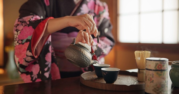 Japanese, hands and matcha for tea ceremony in Chashitsu room with kimono dress and traditional custom. Person, temae and vintage style outfit for culture, fashion and honor with antique crockery
