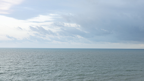 wide sea As far as the eye can see, there is a horizontal line between the sea and the sky. Clearly demarcated The shadows of the clouds give the water a dark color. The surface is streaked in the sam