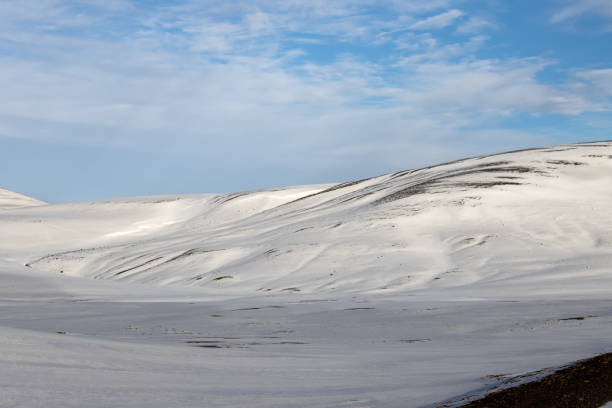 Beautiful autumn day, with a blue sky and white clouds. Fresh snow covering the wold with its waves and small hills. Nord-East Iceland.