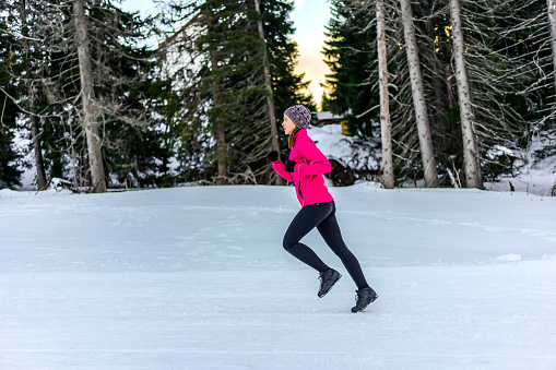 Young sporty woman running outdoor on a snowy winter day