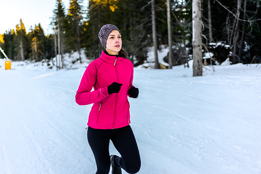 Young sporty woman running outdoor on a snowy winter day