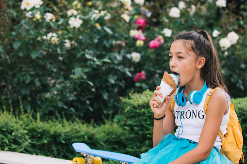 Portrait of teen girl eating ice cream outdoors in the city.