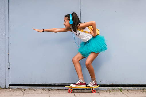 Portrait of beautiful teenage girl with headphones and skateboard