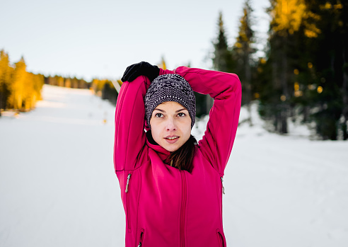 Young woman doing stretching exercises on snowy winter day