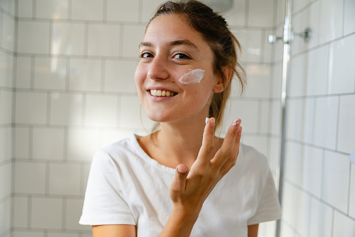 Young woman taking care of her skin with a skin care routine in the morning