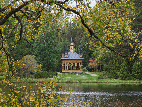 Neogothic style Ruusulaakso (Rose Valley) pavilion near lake in Aulanko nature reserve and recreation area in Finnish city of Hameenlinna: autumn, colorful trees, natural frame.