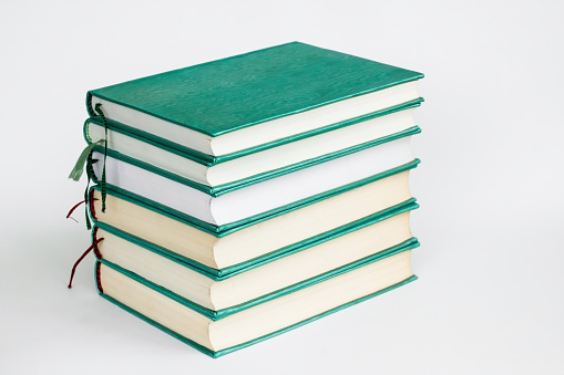 Green colored,hard cover books stacked on white surface with copy space,education concept