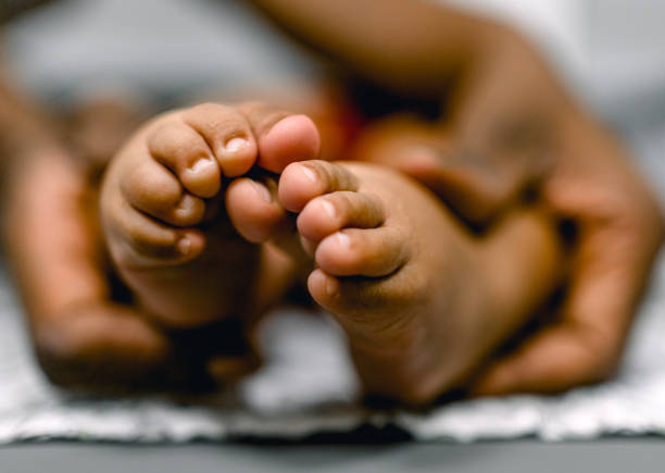 Mother holding tiny foot of newborn baby