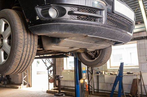 Car raised on car lift in autoservice. Bottom view of a car on a car lift at mechanic's shop.