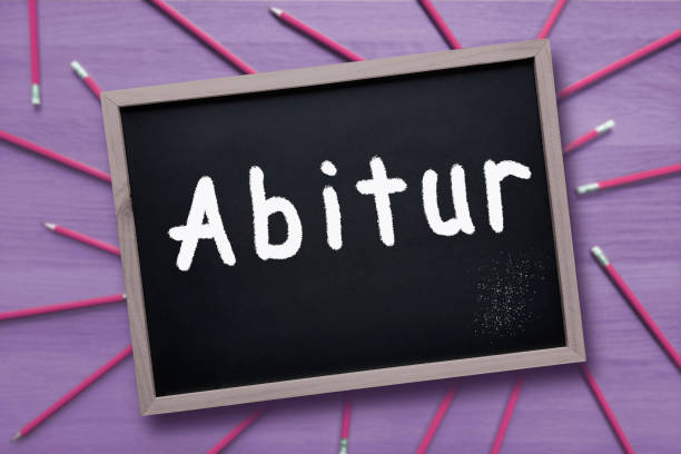 Word is written in chalk on blackboard on blurred purple background with pencils. Preparing and taking Test at gymnasium in Germany, Austria, Norway.