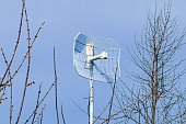 antenna for receiving Internet and Wi-Fi signal in the trees against the blue sky. satellite tracking