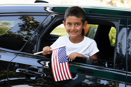 Boy holding American Flag in the car.
