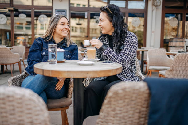 istock Two young woman having coffee while sitting outside at cafe 1993237847