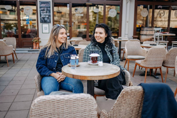 istock Two young woman having coffee while sitting outside at cafe 1993237850