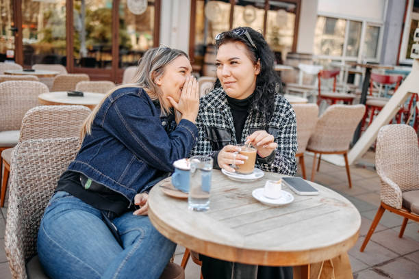 istock Two young woman having coffee while sitting outside at cafe 1993238374