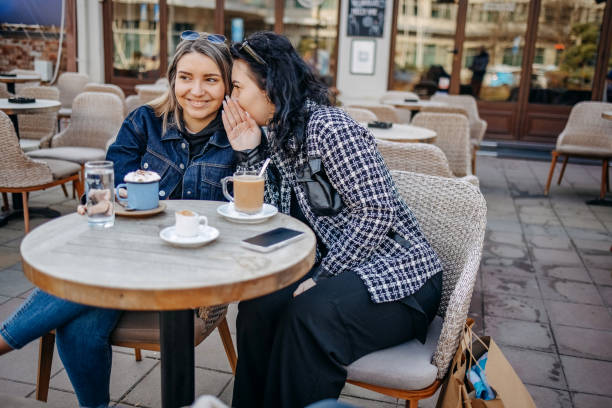 istock Two young woman having coffee while sitting outside at cafe 1993238392
