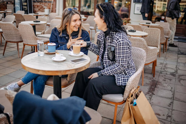 istock Two young woman having coffee while sitting outside at cafe 1993238920