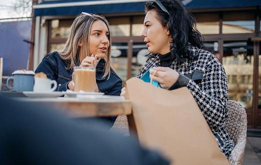 Female friends enjoying while having a coffee break outdoors at restaurant