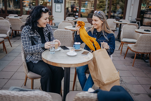 Female friends enjoying while having a coffee break outdoors at restaurant
