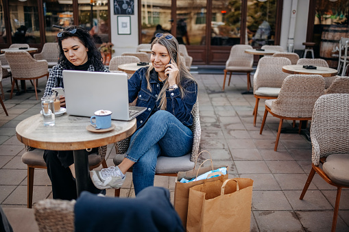 Female friends enjoying while having a coffee break outdoors at restaurant