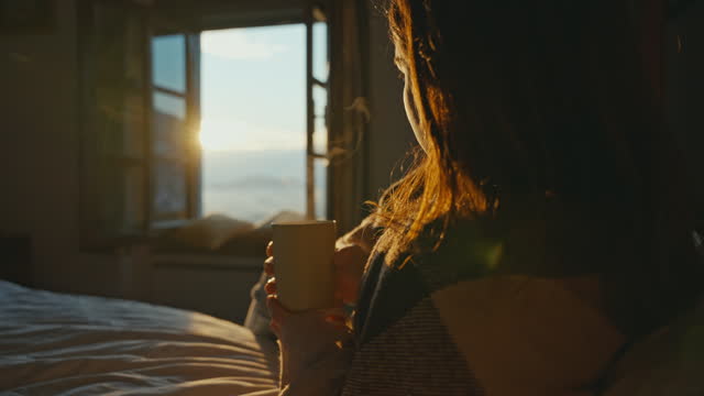 SLO MO Happy Young Woman Drinking Hot Coffee while Reclining on Bed in Apartment in Morning