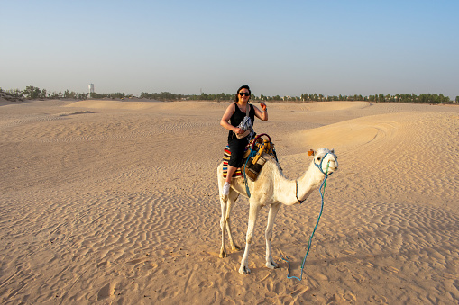 6.11.23 sahara desert, Tunisia: Young woman, Female tourist on camel safari ride at the Sahara Desert in Tunisia, North Africa