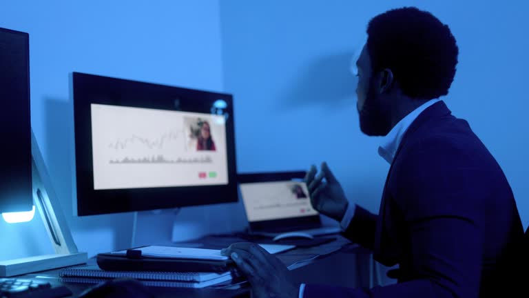 Business African trader investor making stock market analysis video call inside office at night - Financial broker economic concept