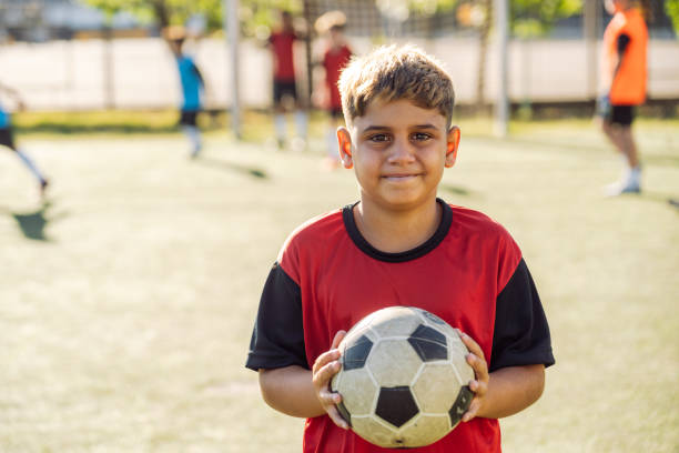 istock Young Boy Smiling with Soccer Ball on Field During Daytime 1993338273