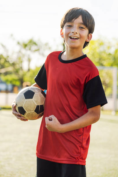 istock Smiling Boy Holding Soccer Ball Standing on Field in Uniform 1993338826