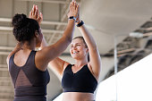 Two cheerful plus-size women in fitness wear giving high five after a workout. Women athletes during fitness training outdoors giving high five.