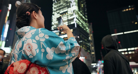Japanese woman, picture and night with smartphone, social media and connection with network, traditional clothes and journey. Digital app, evening and person with a cellphone, blog post and adventure