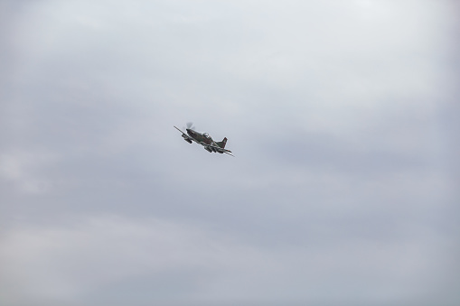 An military airplane in the sky flying with cloudy sky.