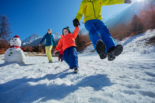 Funny family with kids plays winter games enjoying vacations in beautiful mountain resort